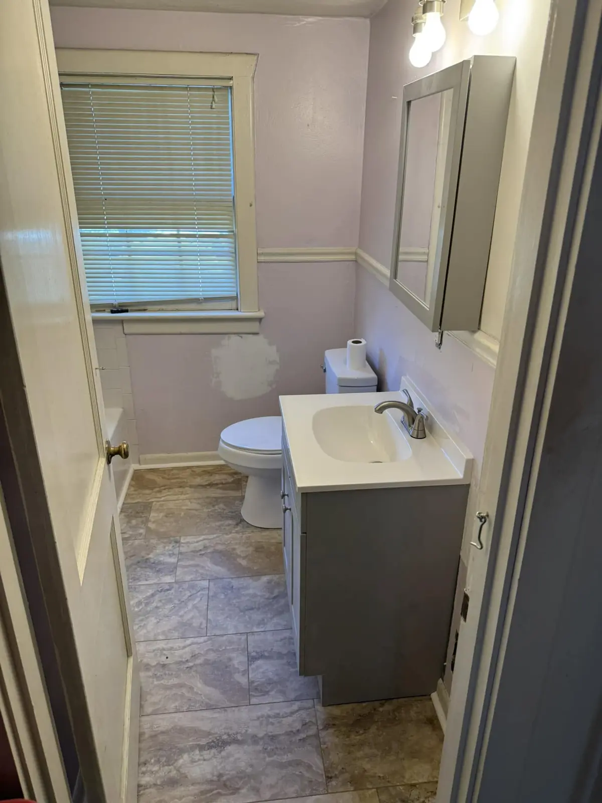 Bathroom work in progress with new flooring, vanity, toilet, lighting, and medicine cabinet