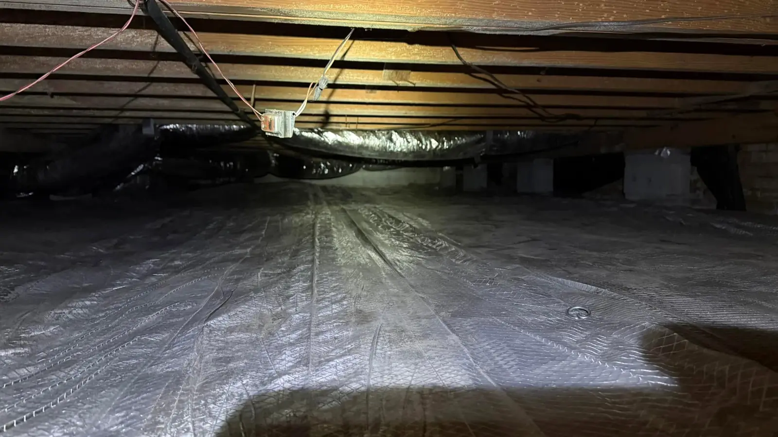 New vapor barrier covering a crawlspace floor and fitted around its supports