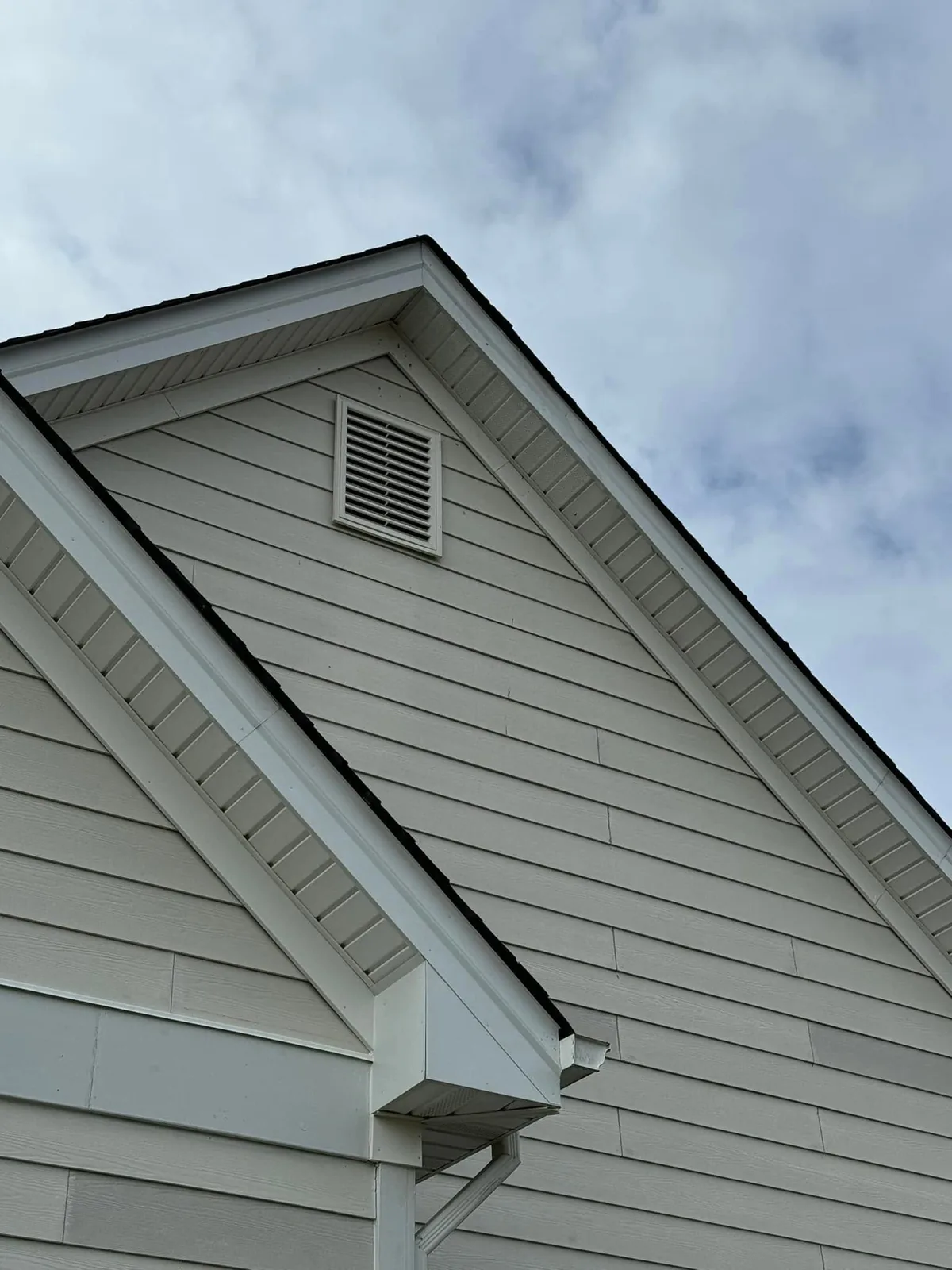 Replacement soffit panels beneath the sloping roof edges of a sided home