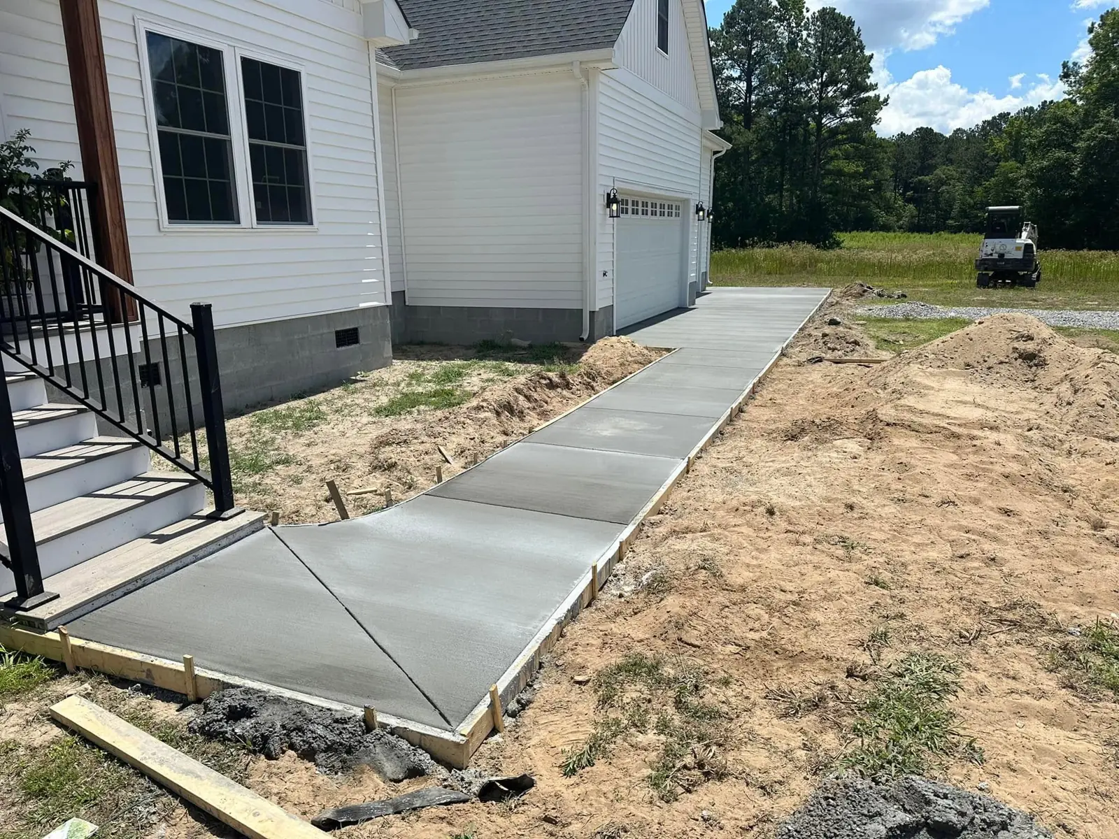 Concrete walkway beside a home connecting to an apron, with formwork still in place